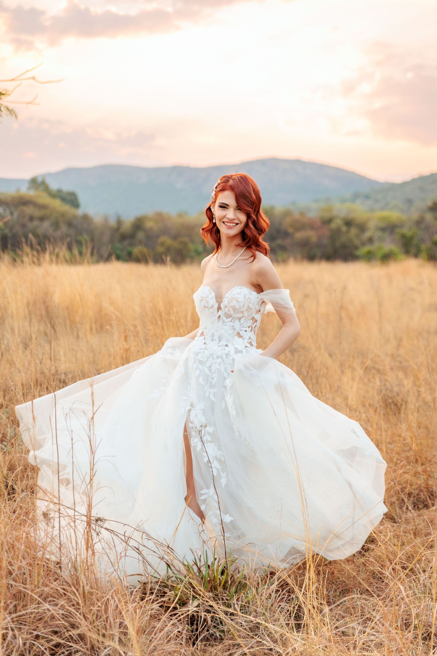 A bride in a flowing white dress twirls joyfully in a sunlit meadow at golden hour.