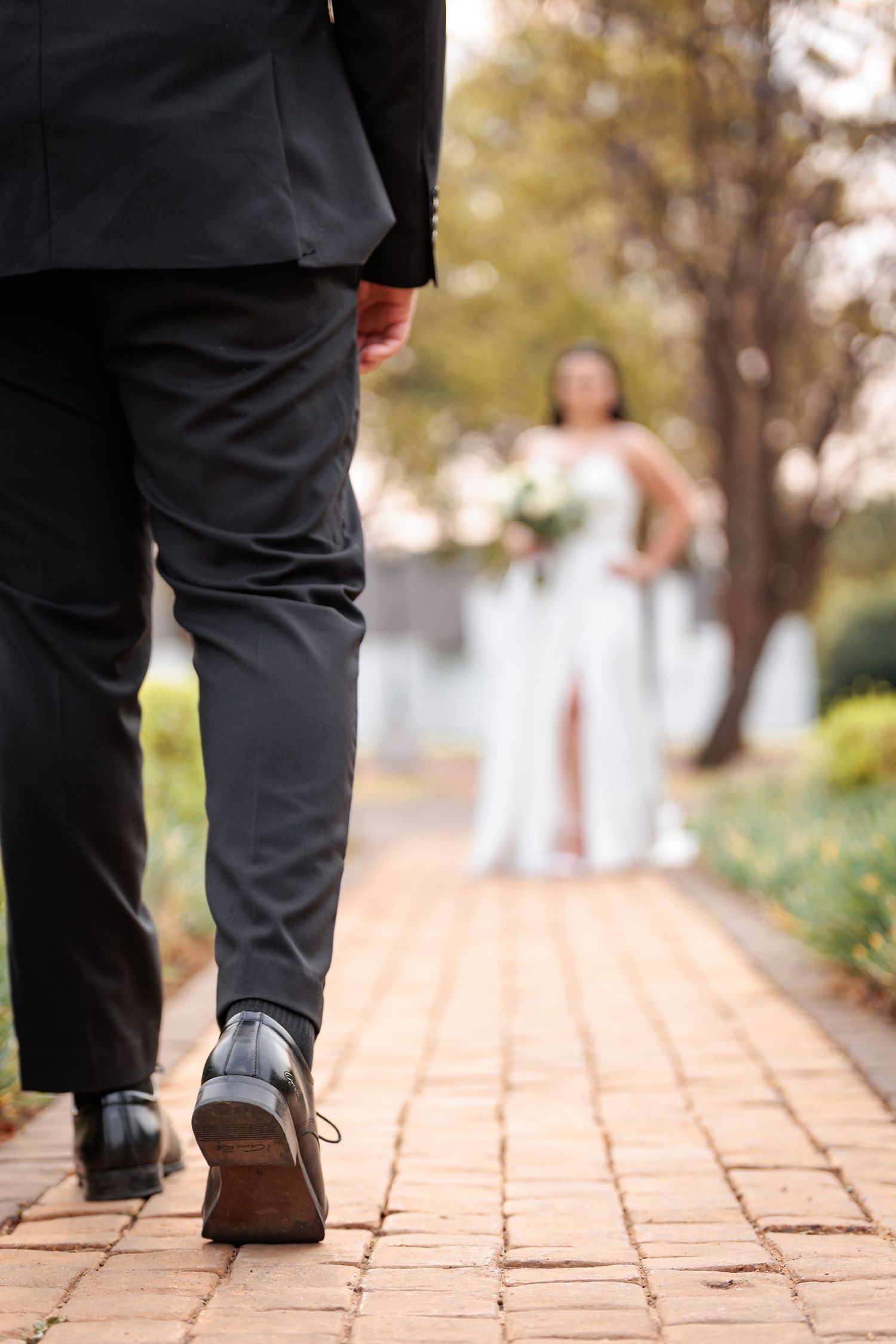Close up of formal shoes walking on brick pathway during wedding ceremony.