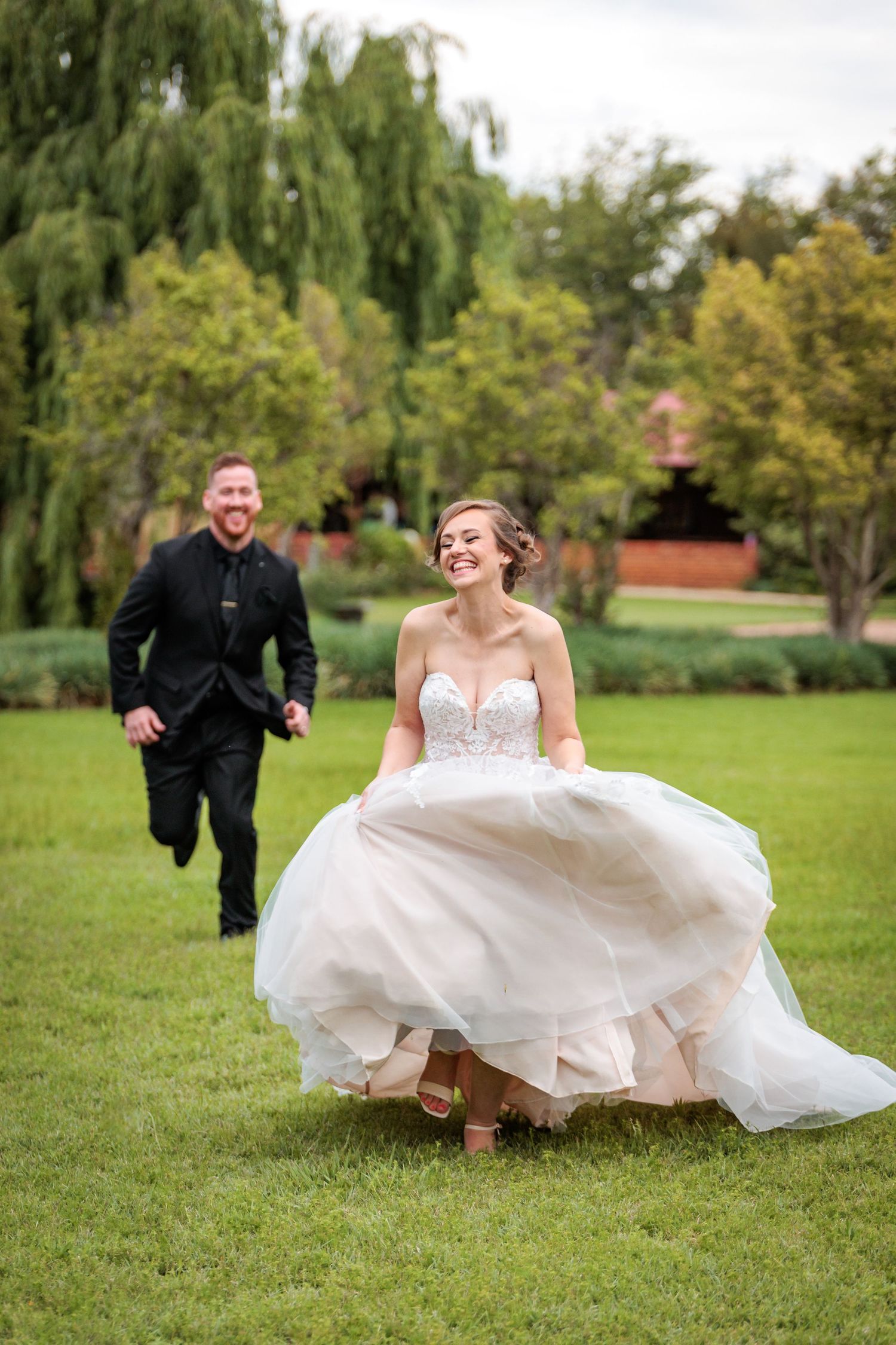 A sequence of playful wedding photos shows a couple running and laughing across a green lawn with willow trees in the background.