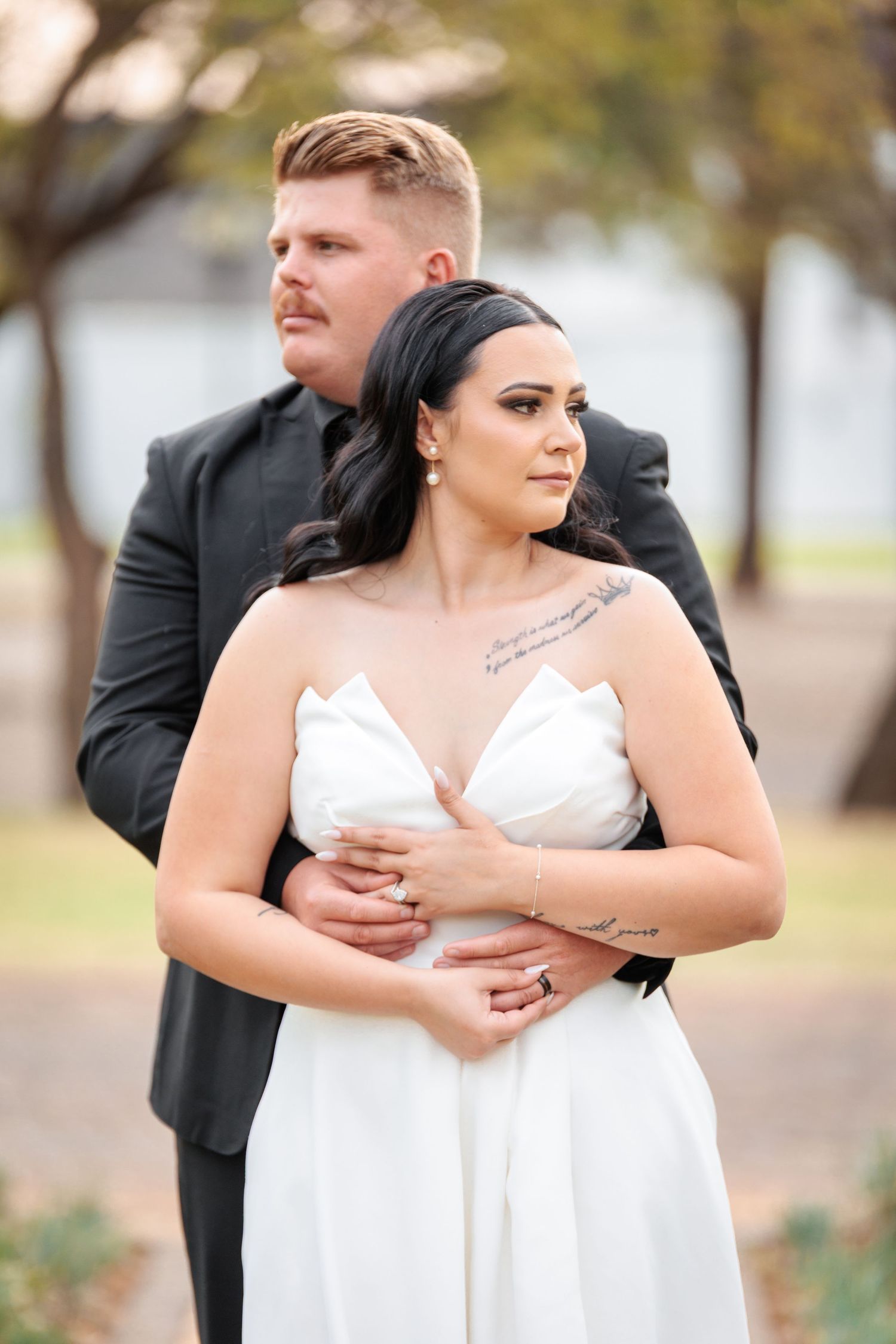 A romantic wedding moment captured with a couple embracing outdoors in formal attire.