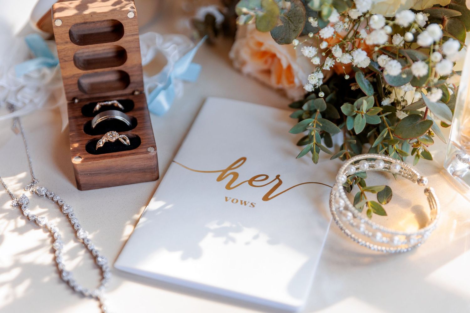Wedding details including rings and delicate flowers arranged on a light surface.
