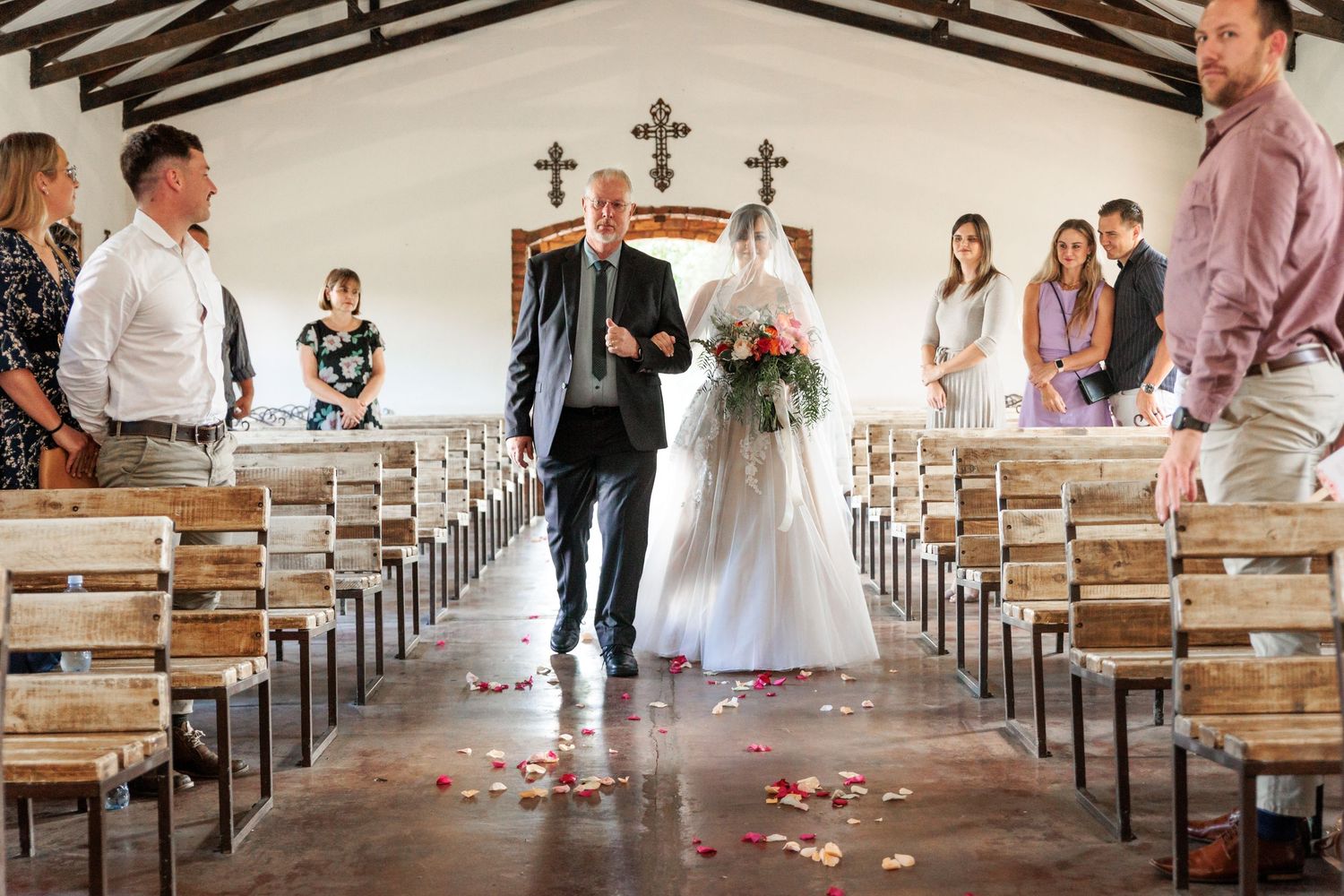 A panoramic collage of wedding ceremony moments in a church with wooden pews and scattered rose petals down the aisle.