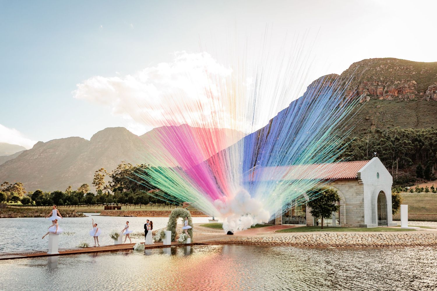 Colorful rainbow light trails created by long exposure photography illuminate a scenic beach landscape at sunset.