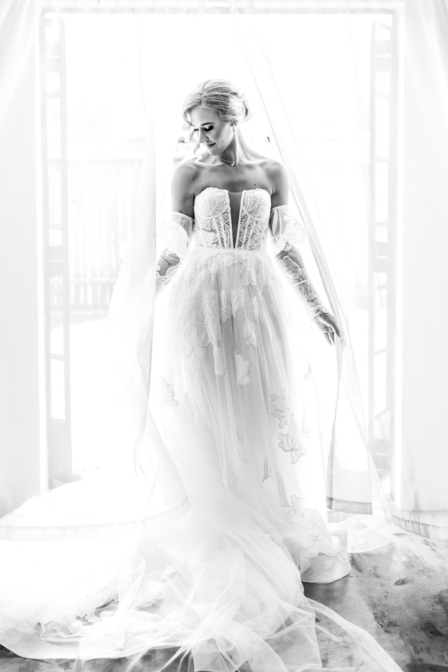 A series of ethereal black and white bridal portraits showing a flowing wedding gown in soft window light.