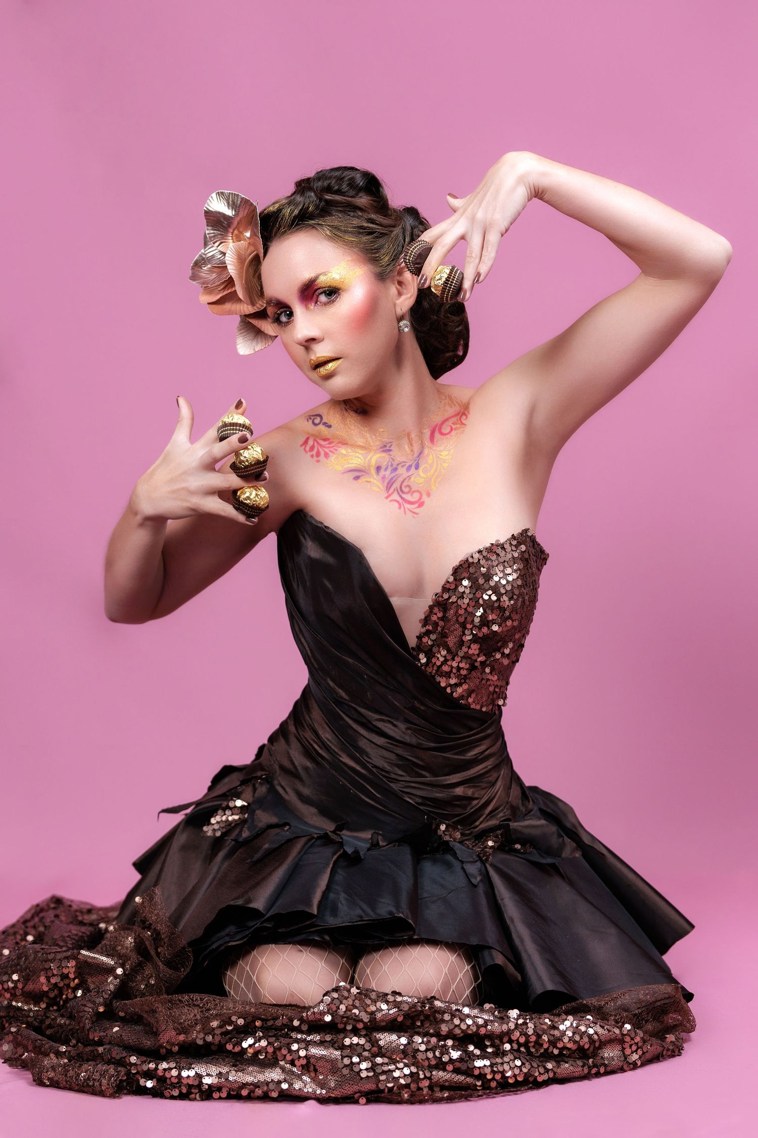 A model in a brown sequined dress poses gracefully against a pink background in a creative fashion photoshoot series.