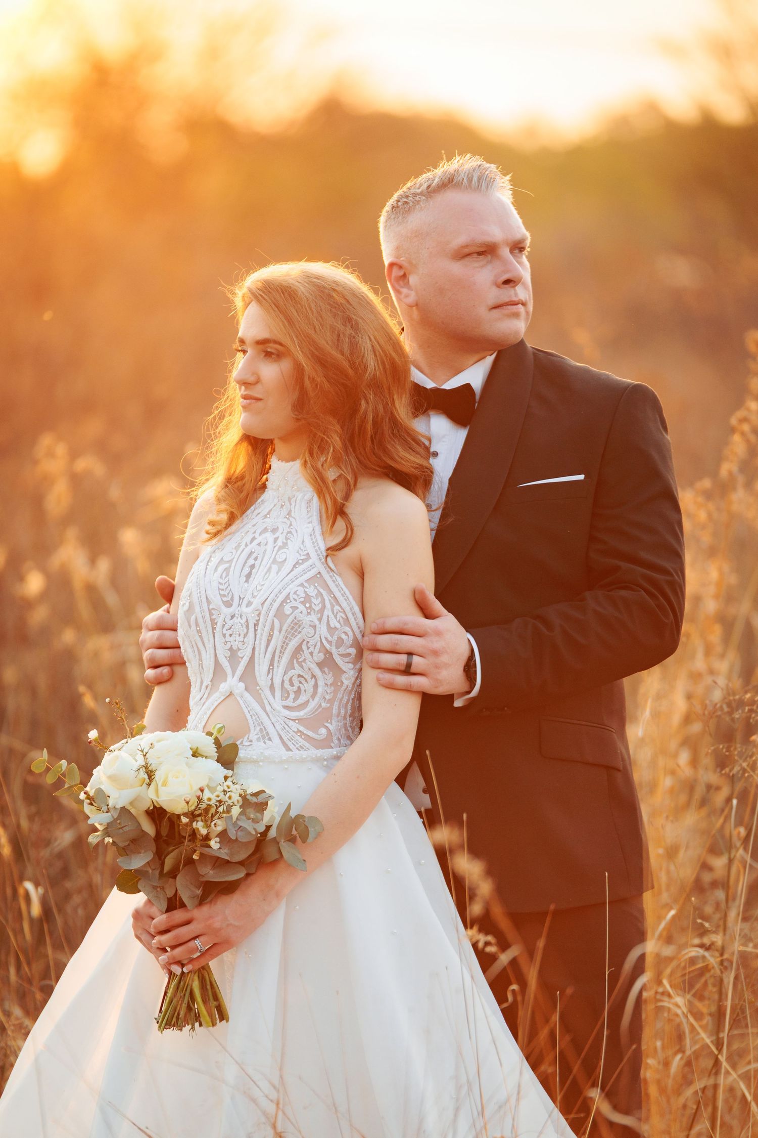 Sunset wedding portrait in tall grass with elegant white bouquet.
