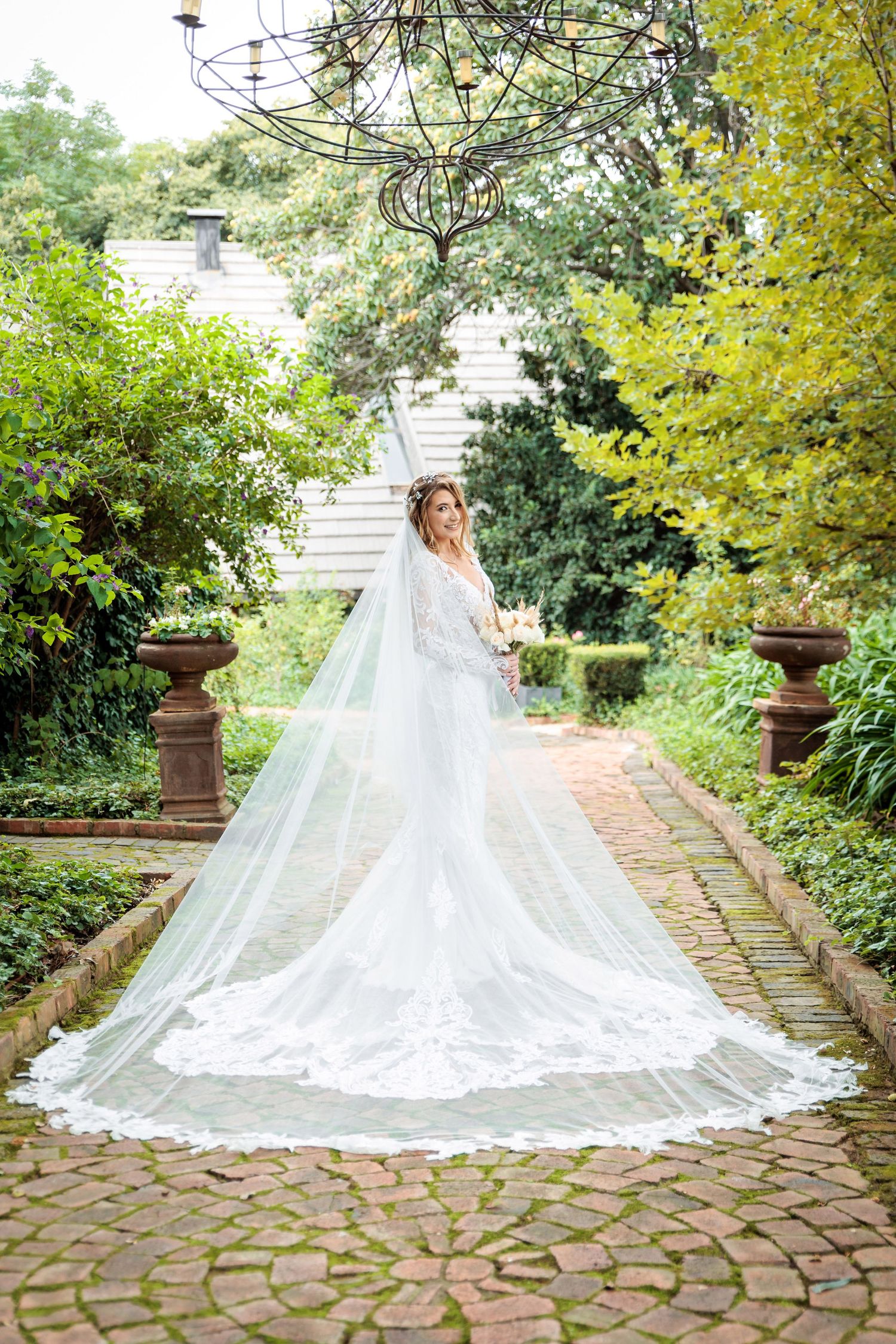 Dramatic cathedral length veil trailing on stone pathway in garden.