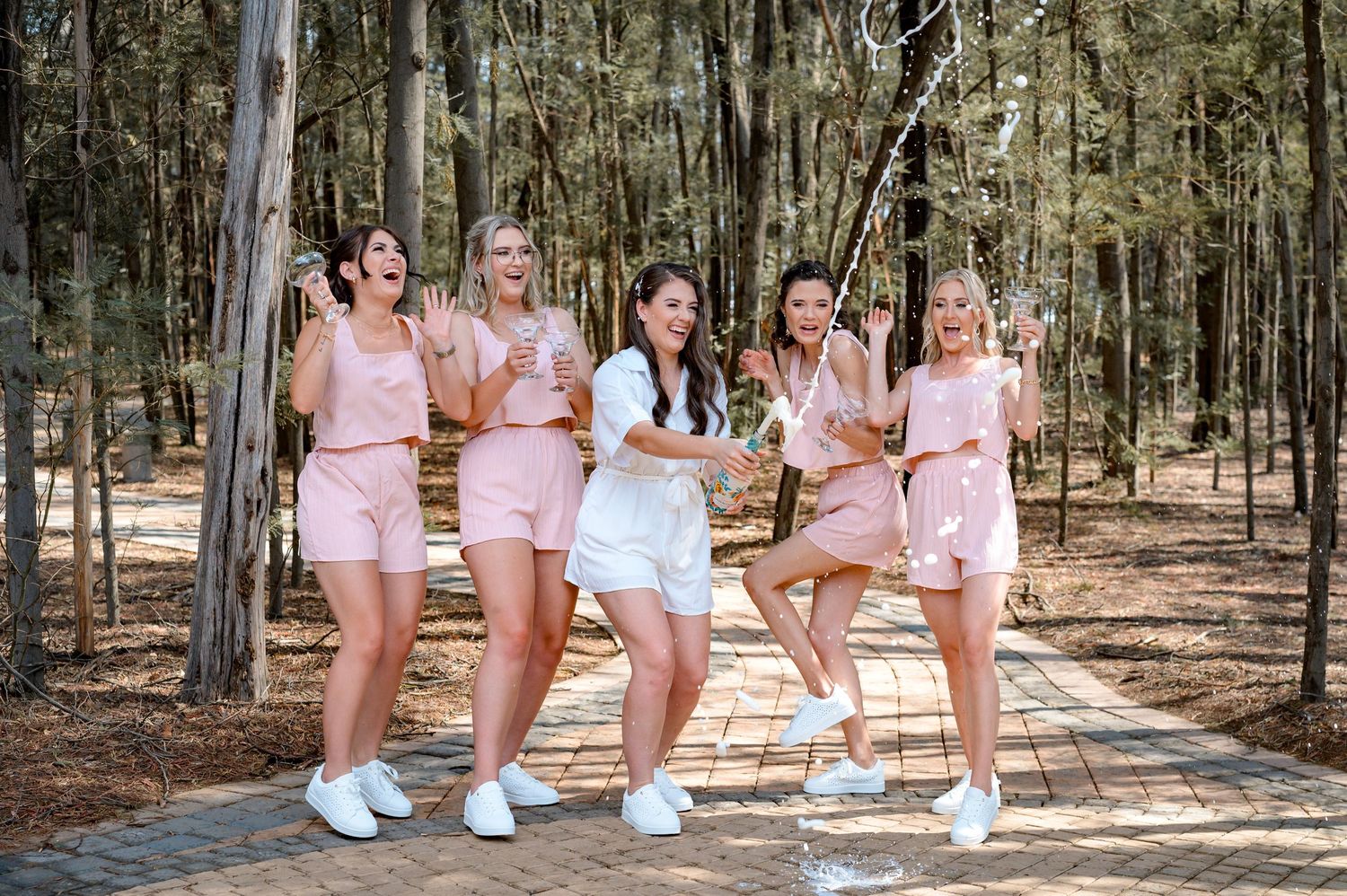 A group in matching pink outfits sits together on a log in a wooded setting.