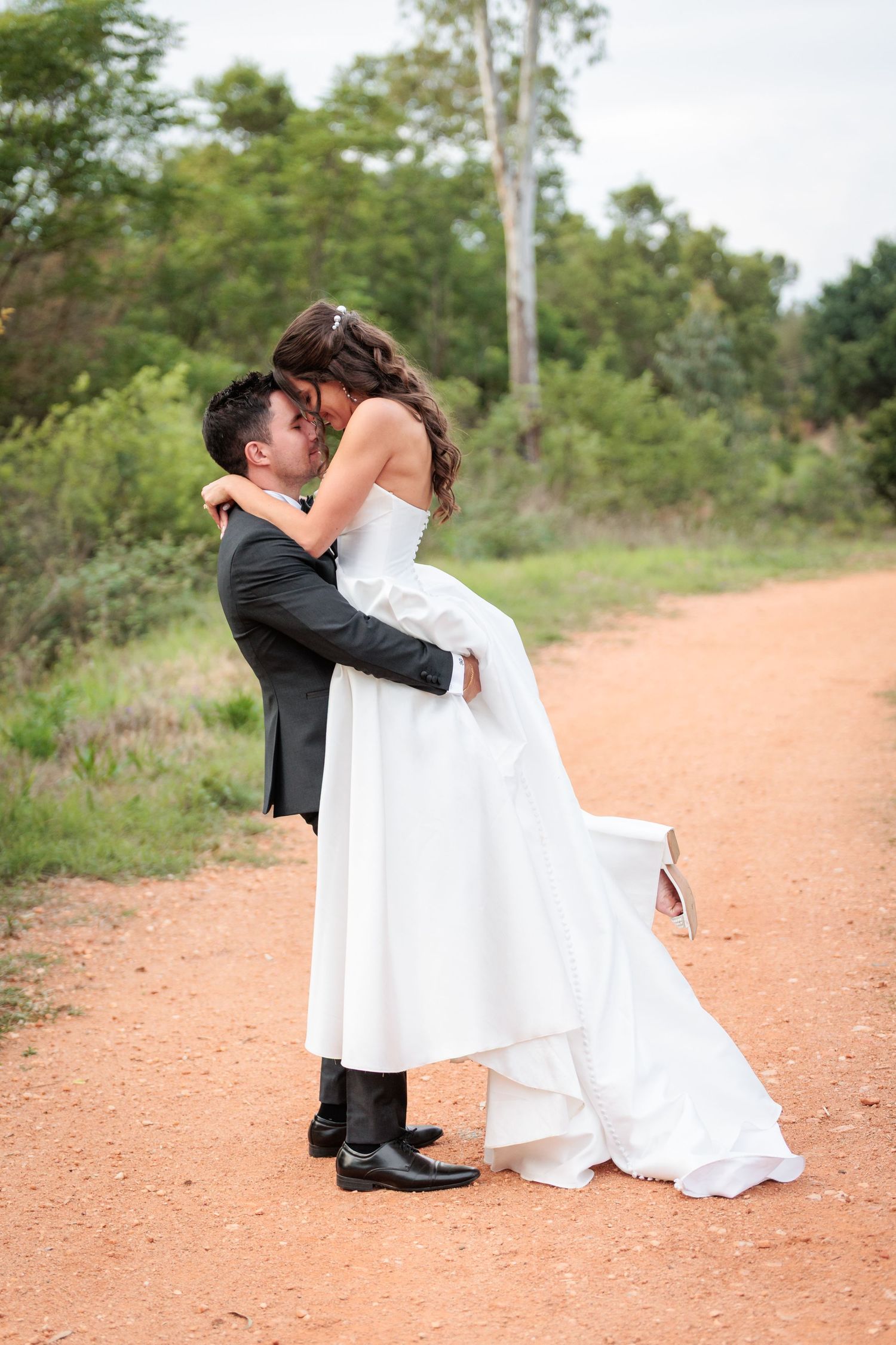 A romantic wedding couple shares intimate moments on a rustic dirt road in a series of four connected photos.