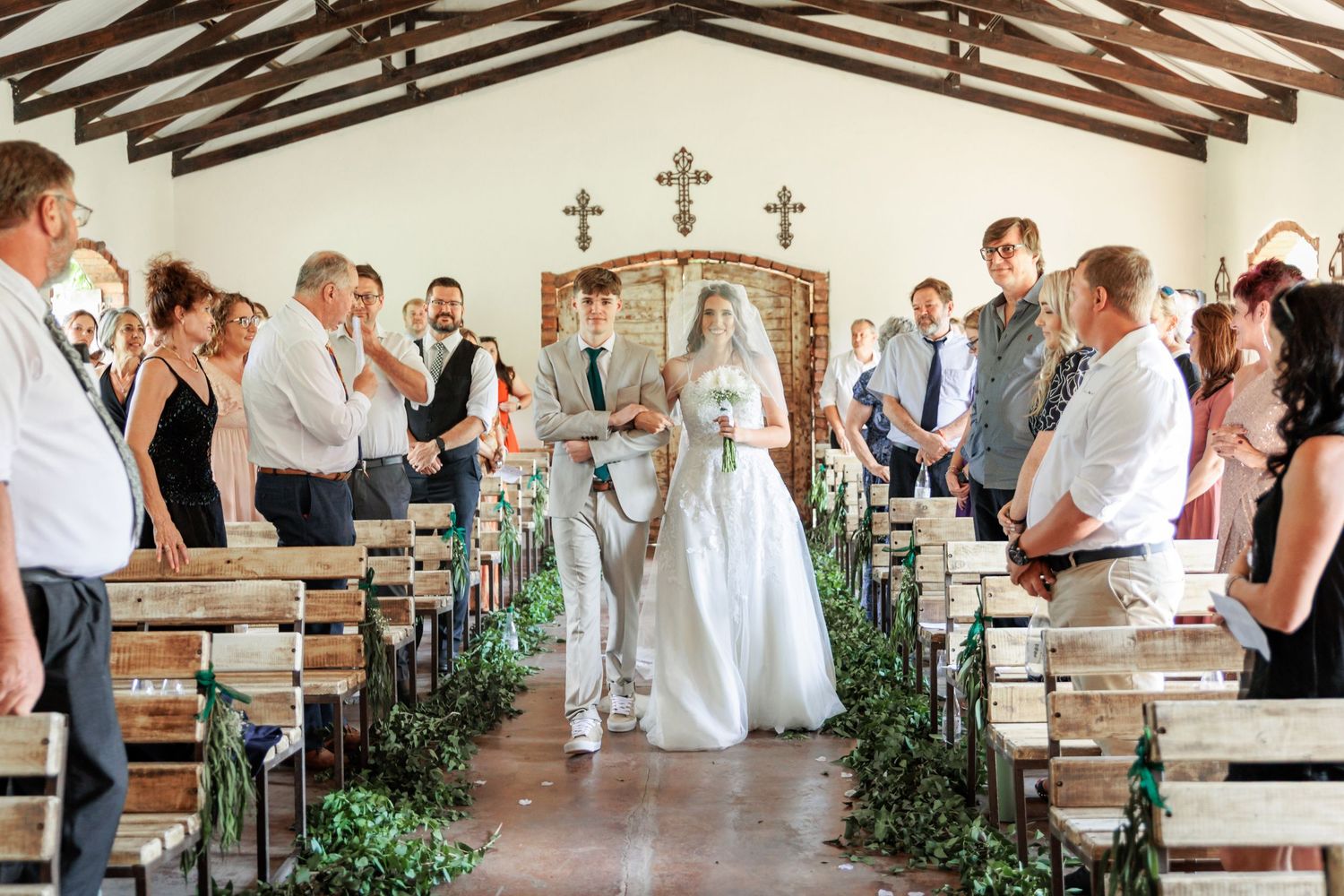 Interior of a rustic chapel decorated for a wedding ceremony with wooden beams and crosses.