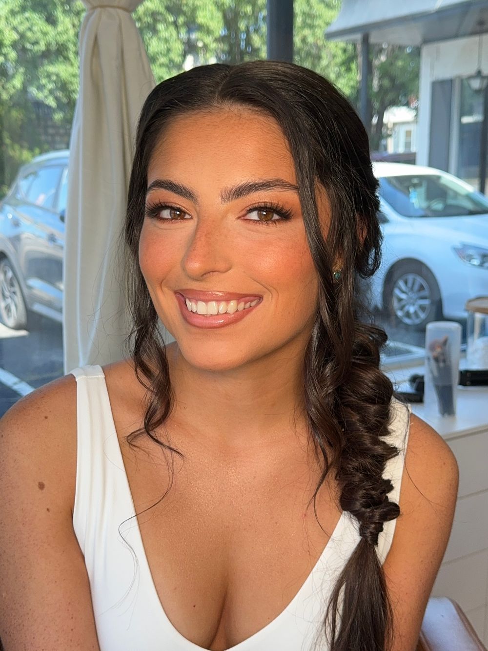 Outdoor bridal portraits showcasing natural makeup and dark wavy hair against a sunny background.