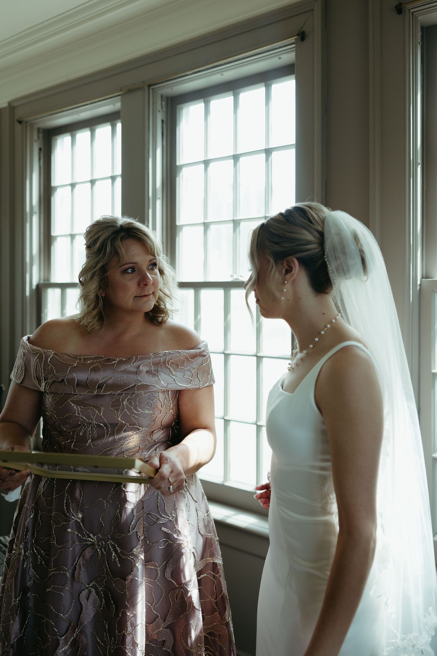 Wedding preparation scene with elegant dresses and natural window light.