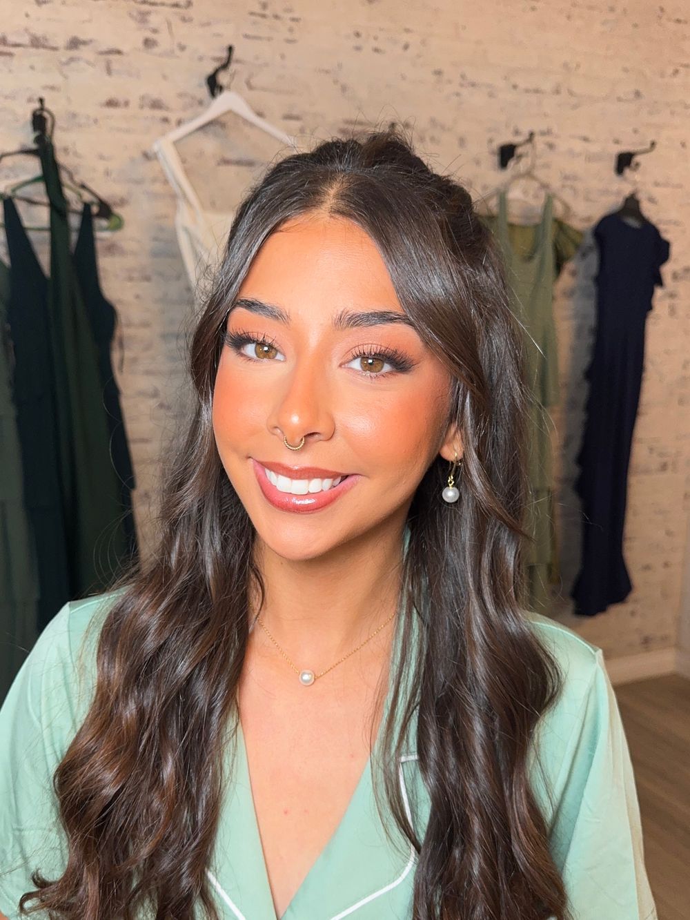 Professional beauty shots in a mint green blouse with styled dark hair and glowing makeup.