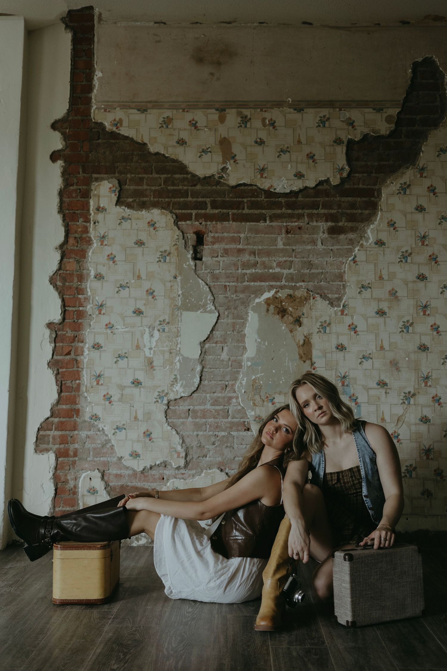 Two people lounging on furniture against an exposed brick wall.