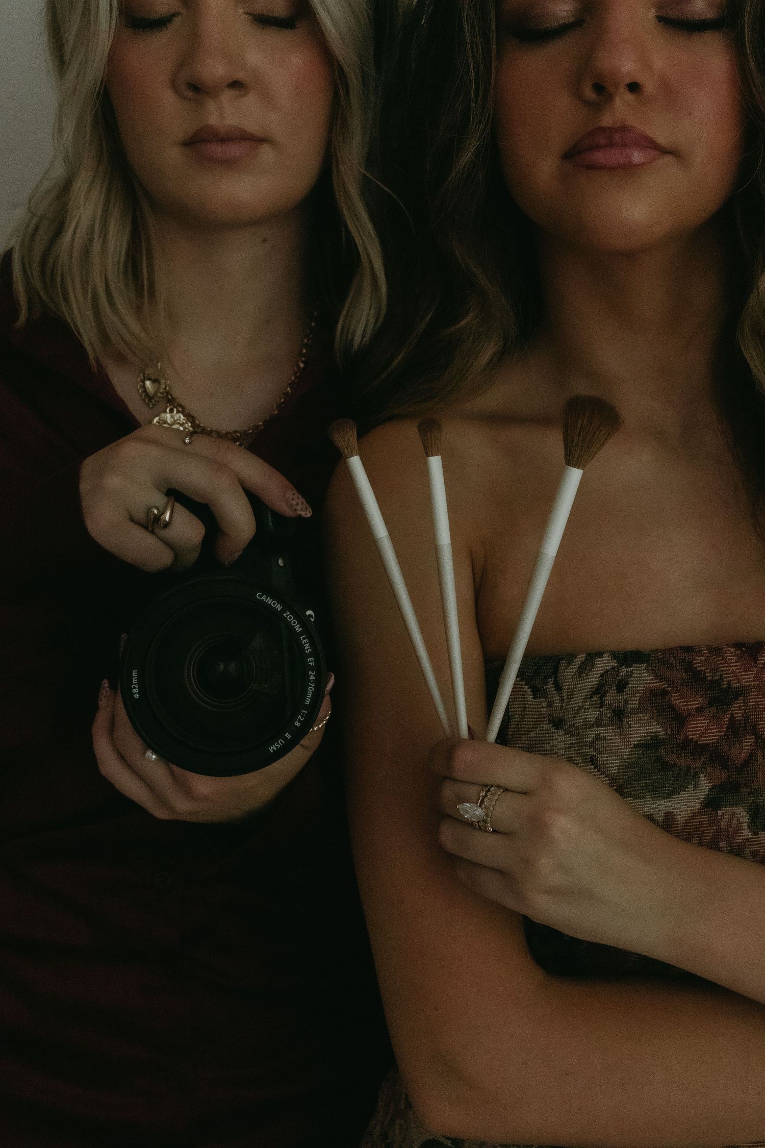 Close-up shot of hands holding white candles in dim lighting.