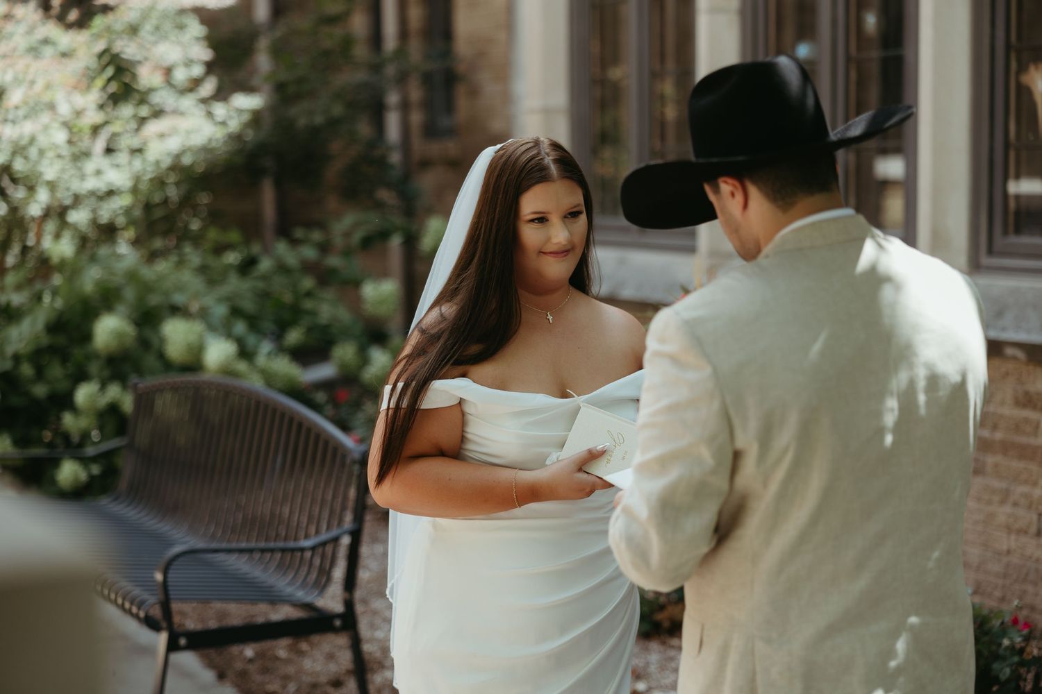 A romantic first look sequence between newlyweds against a brick building backdrop.