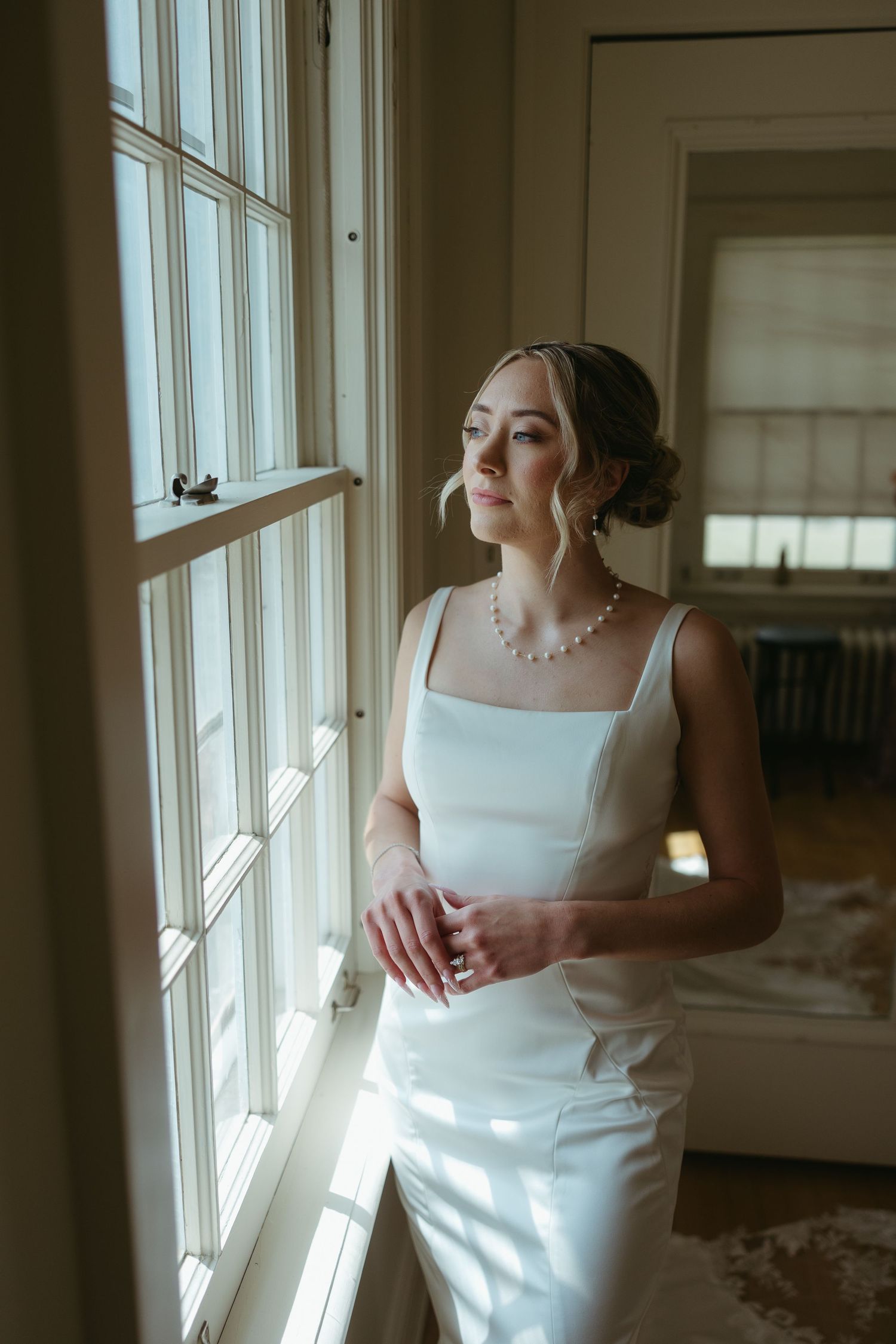 Elegant bridal portrait series by a sunlit window with natural lighting.