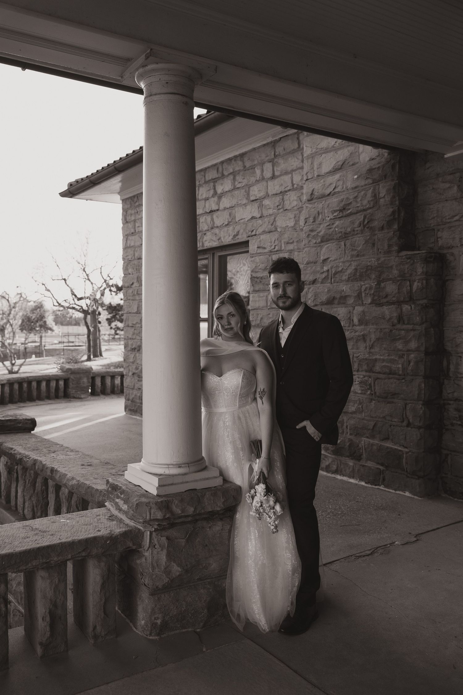 Couple poses under stone archway of historic building during formal photo session.