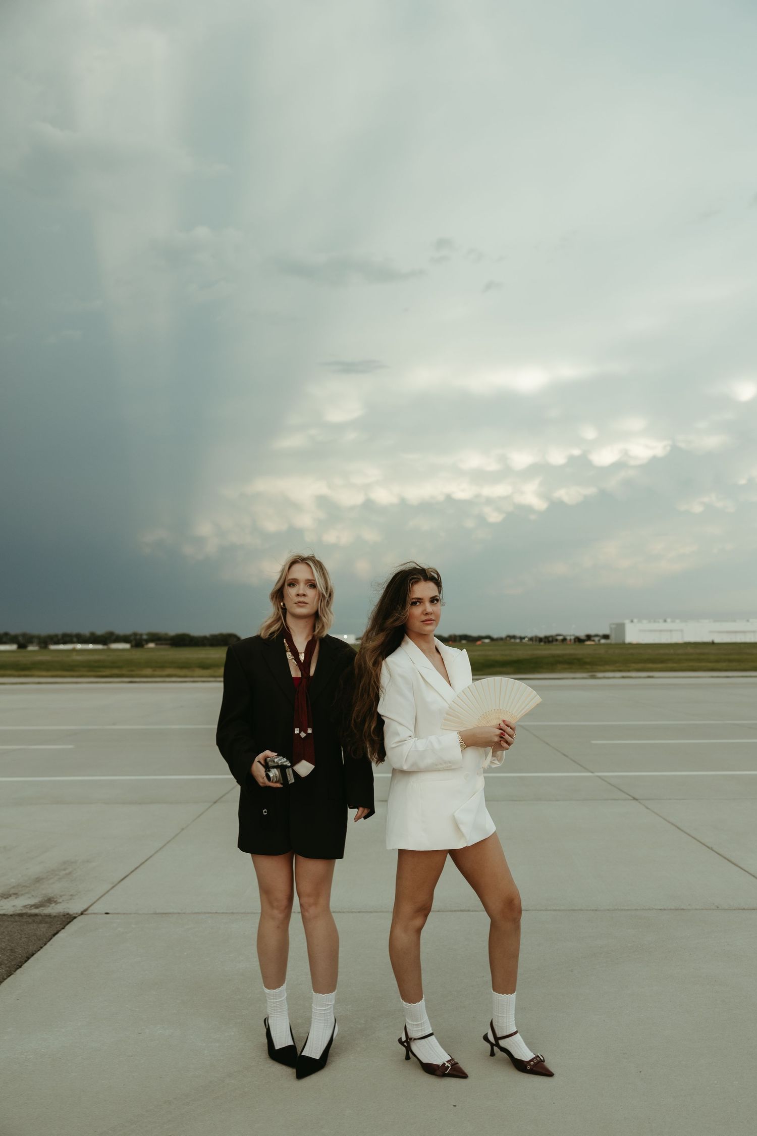 Two people in contrasting outfits posing on an empty airport runway.