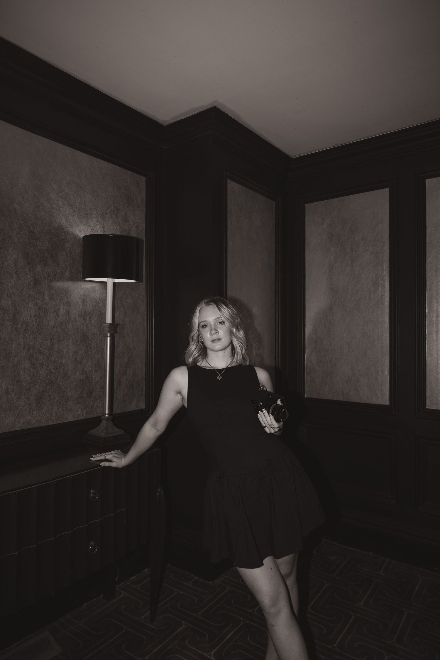 An artistic black and white portrait in an elegant dark room with modern lighting.