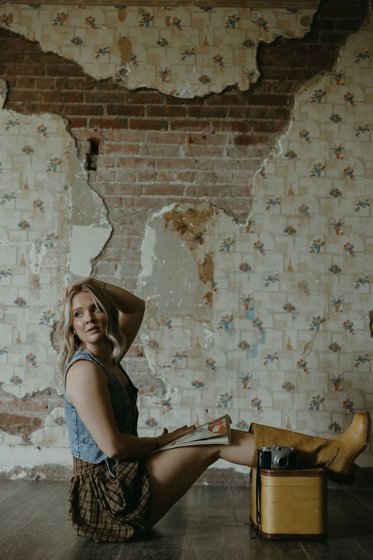 Artistic boudoir photo session in rustic room with peeling wallpaper and exposed brick wall.