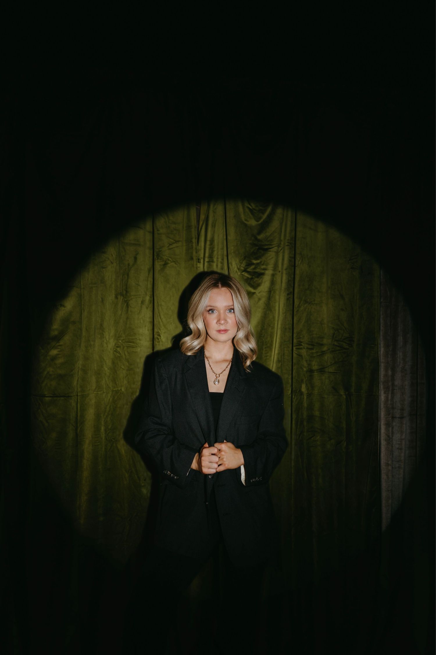 Moody sequence showing figure in black attire against yellow-tinted curtain background.