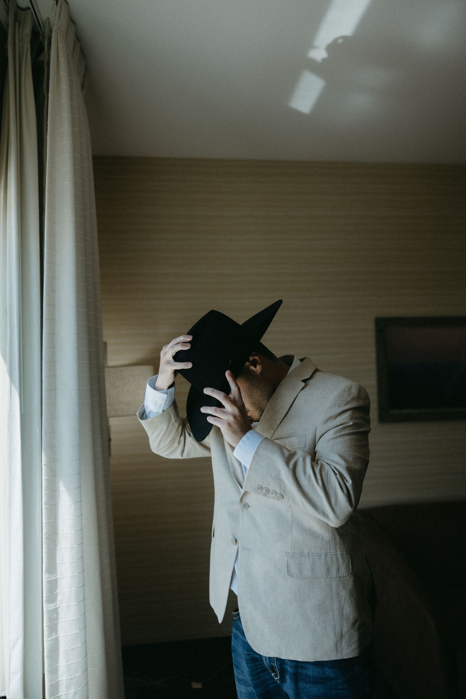 Person in light colored suit and cowboy hat moves dramatically indoors.