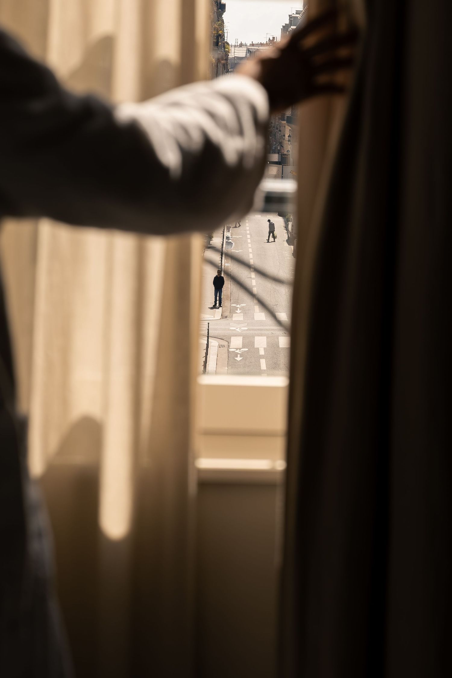 Guest opening the curtains of a luxury suite at Mondovi Luxury Suites in Paris overlooking a Parisian street
