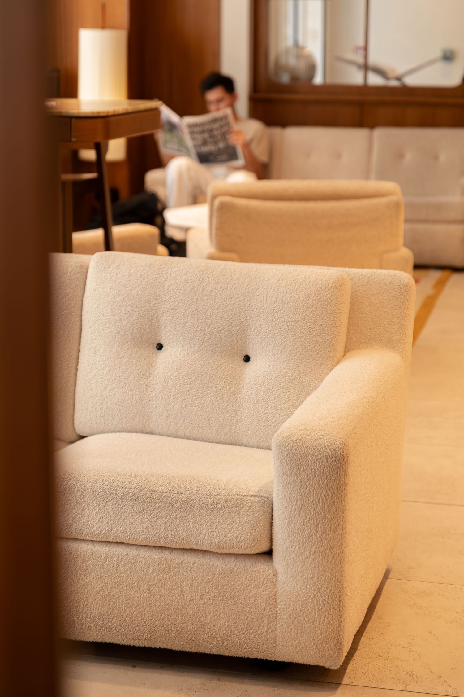 Guest reading a newspaper in the design lobby of Hôtel Padam in Paris