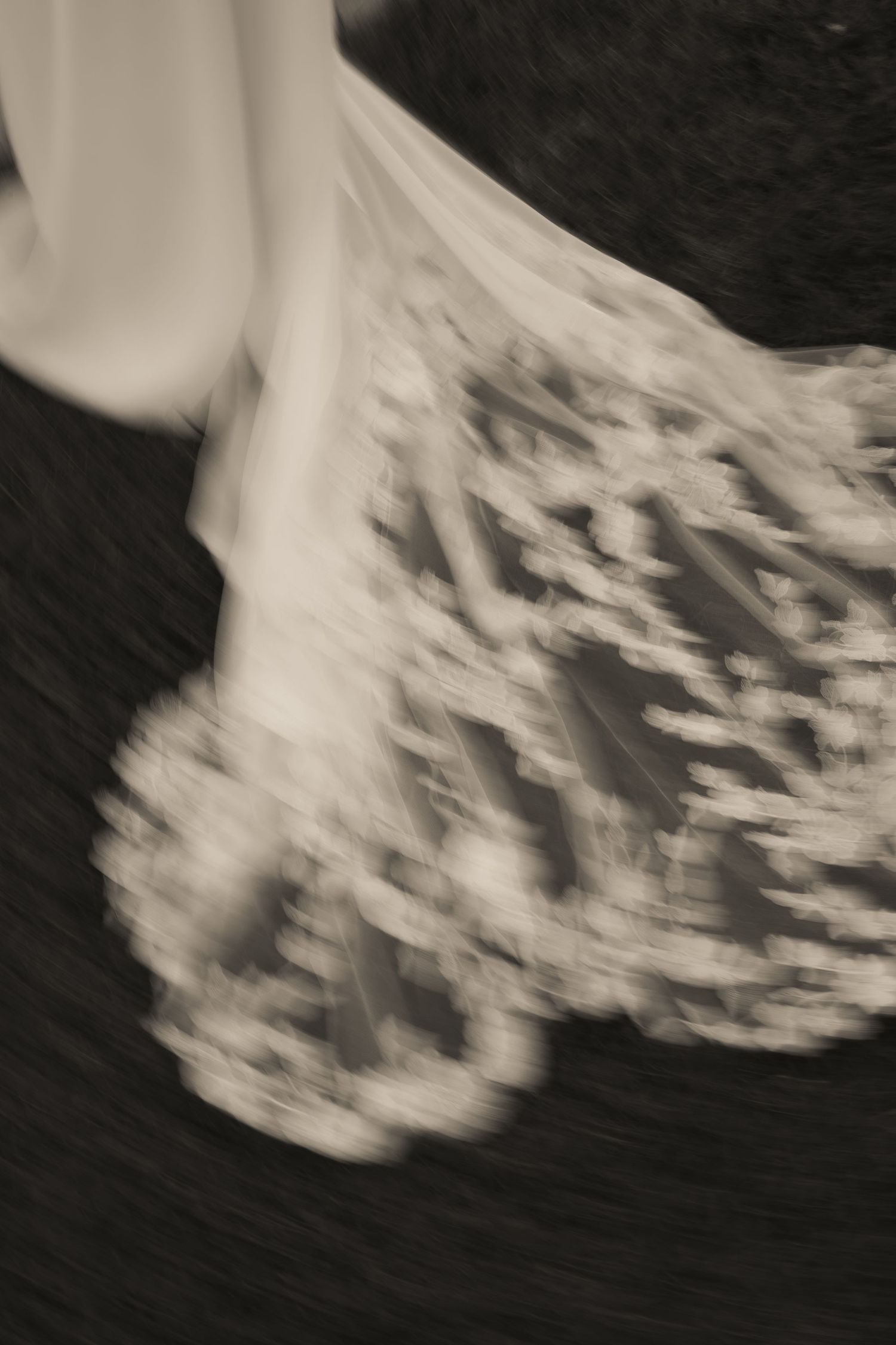 Black and white artistic photograph of the bride's lace train in motion