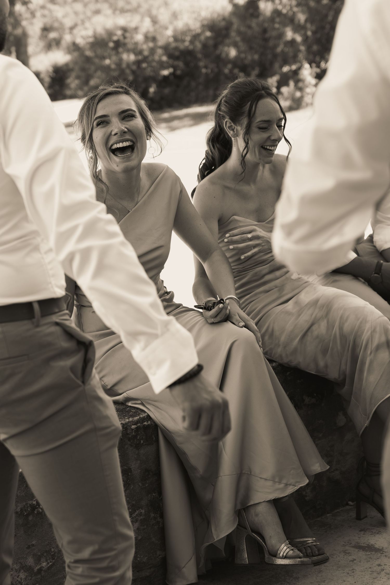 Black and white portrait of bridesmaids and groomsmen laughing together outdoors