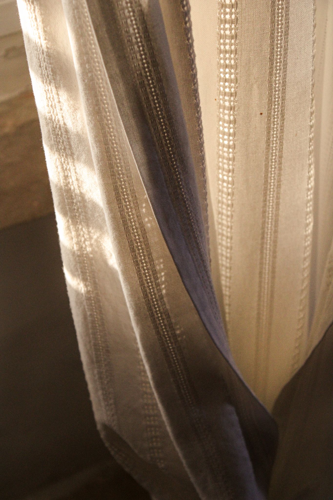 Soft morning sunlight illuminating a flowing curtain in a boutique hotel in Puglia