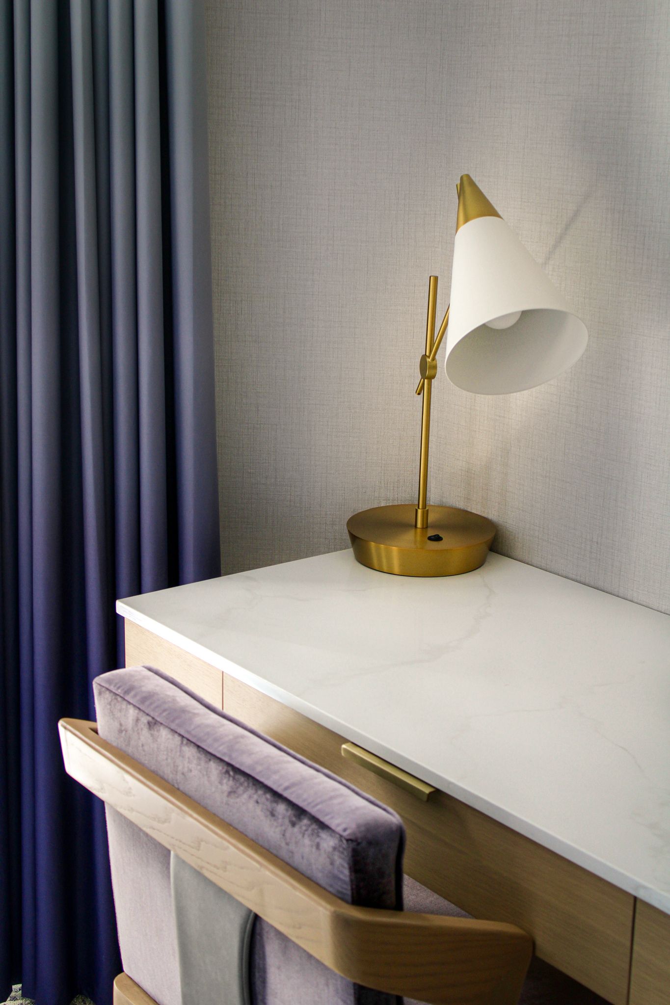 Elegant workspace in a luxury suite at Iris Hotel Boston featuring a wooden desk, velvet chair and brass details