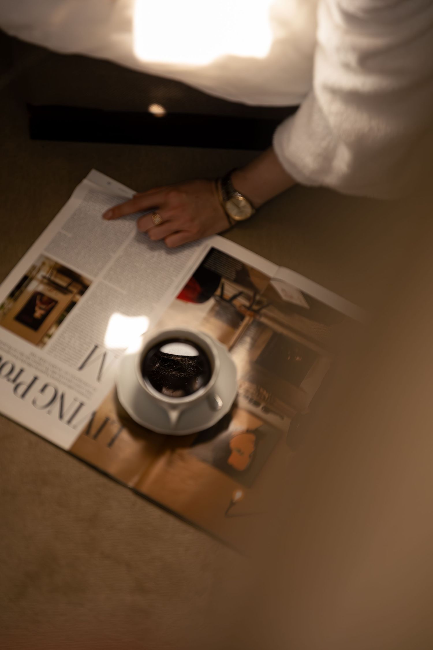 Guest enjoying coffee and reading a magazine on the bed of a luxury suite in Paris