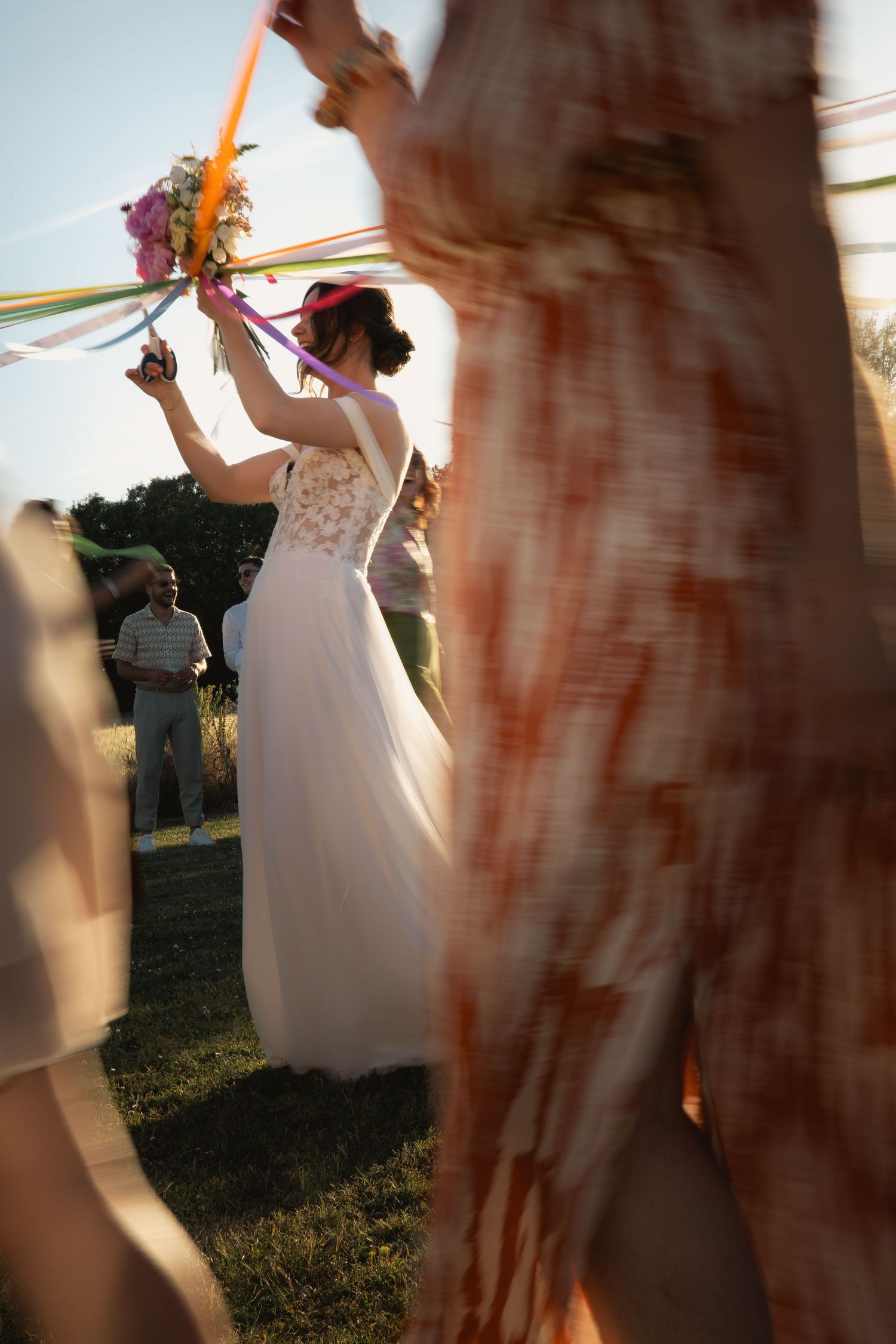 Bride cutting the ribbons attached to her bouquet surrounded by her female guests
