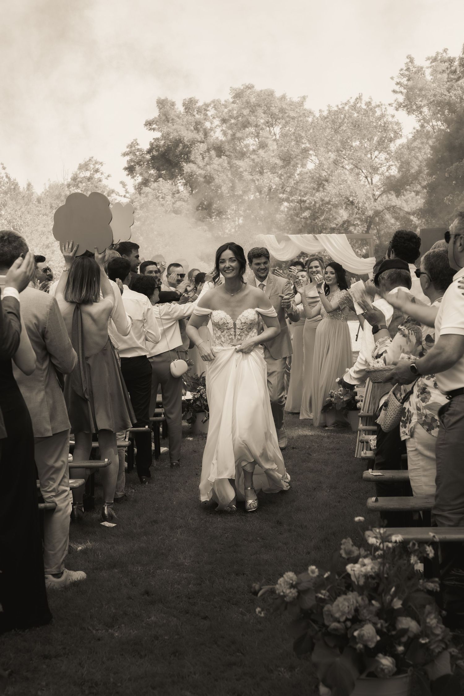 Bride and groom leaving their outdoor wedding ceremony as guests applaud and celebrate