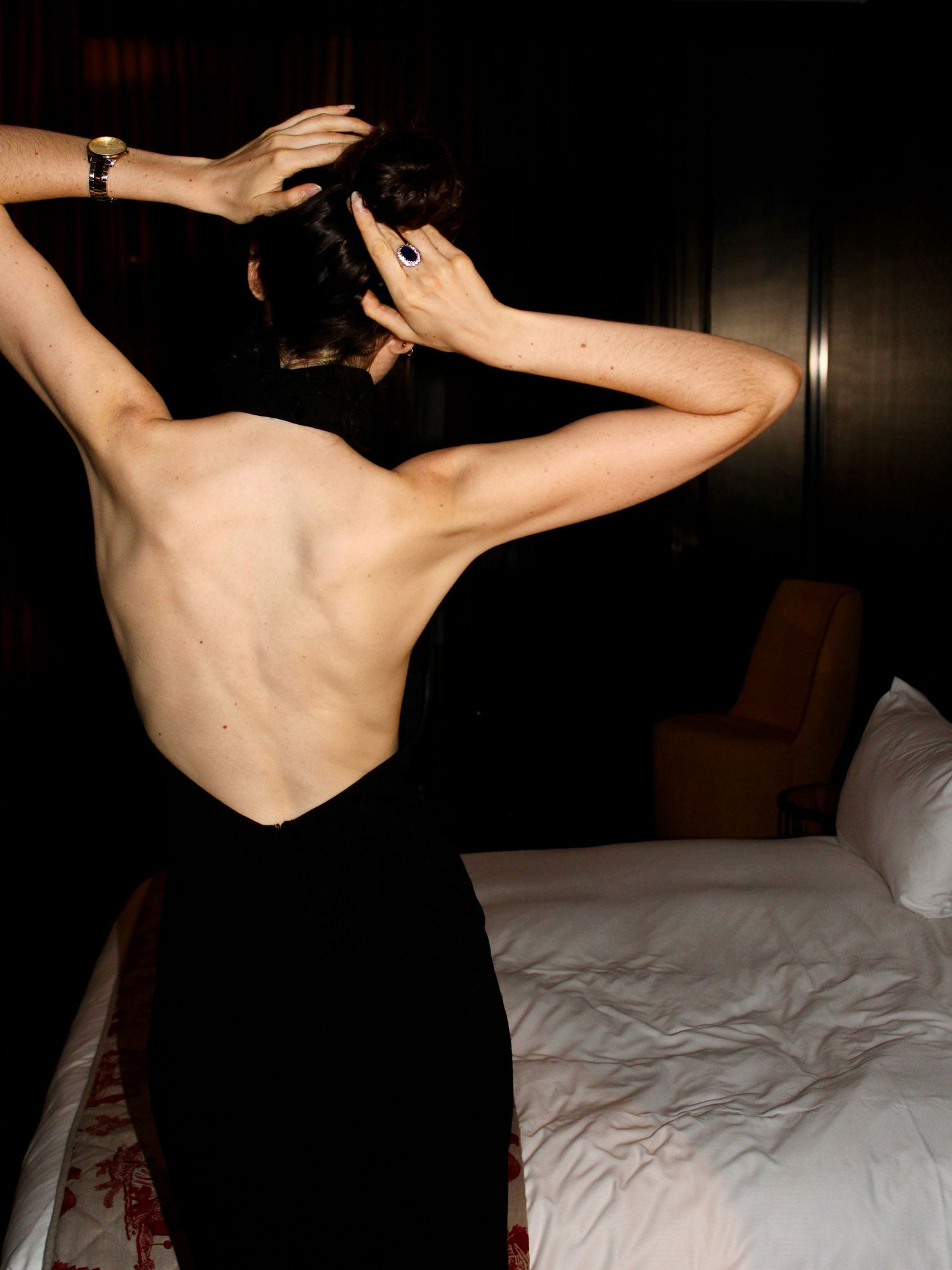 Woman getting ready in a luxury suite at W Philadelphia wearing an elegant black backless dress