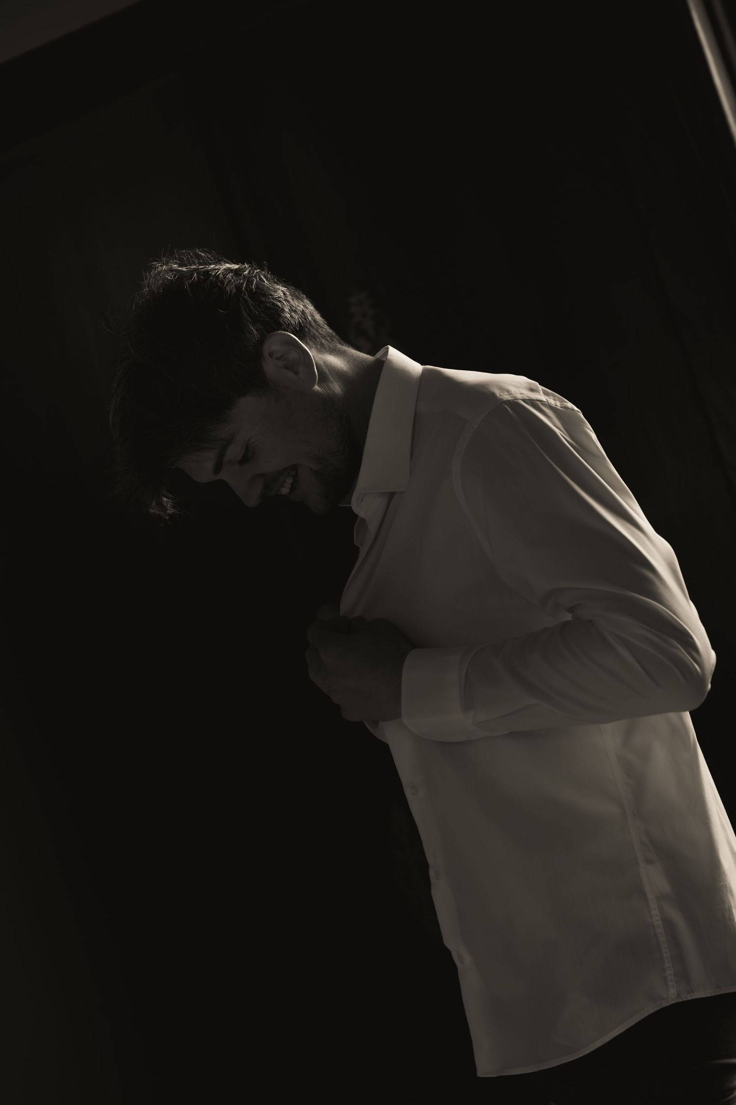 Black and white photograph of the groom getting dressed during the wedding preparations