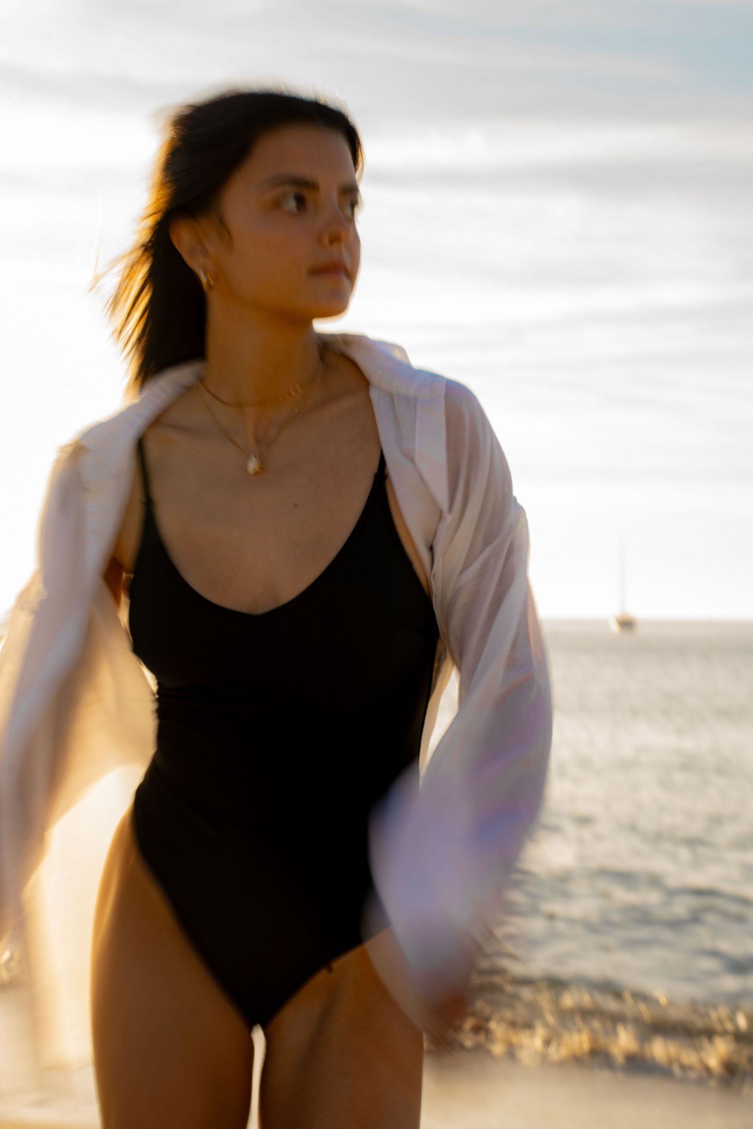 Portrait of a woman in movement on the beach in warm natural light, with ocean and soft tones creating a cinematic mood.