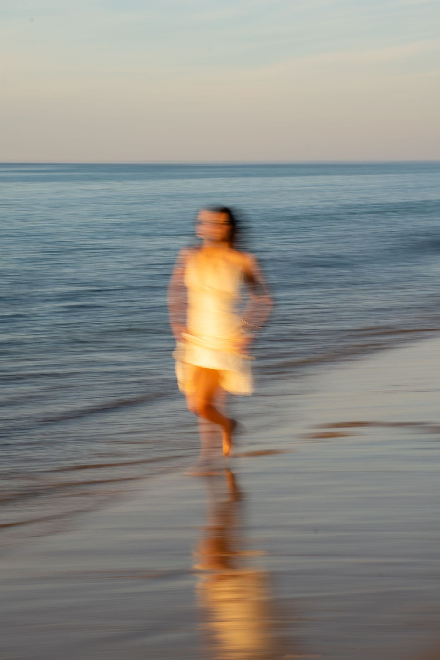 Portrait of a woman on the beach in warm natural light, with ocean and soft tones creating a cinematic mood.