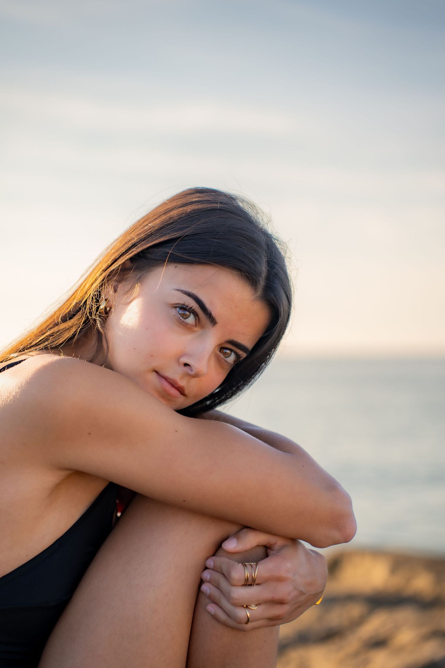 Portrait of a woman on the beach in warm natural light, with ocean and soft tones creating a cinematic mood.