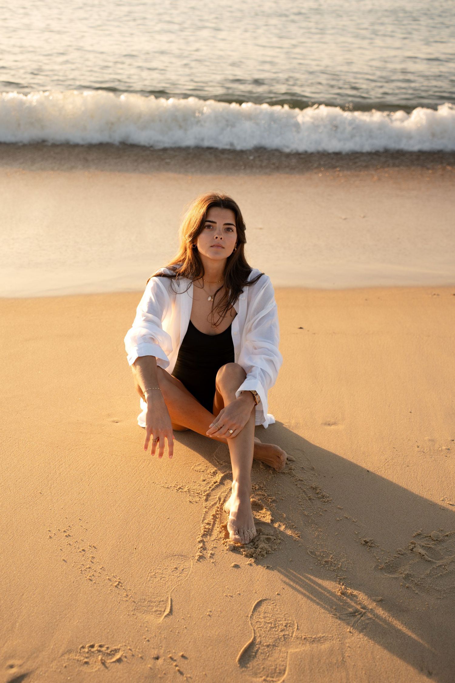 Portrait of a woman on the beach in warm natural light, with ocean and soft tones creating a cinematic mood.