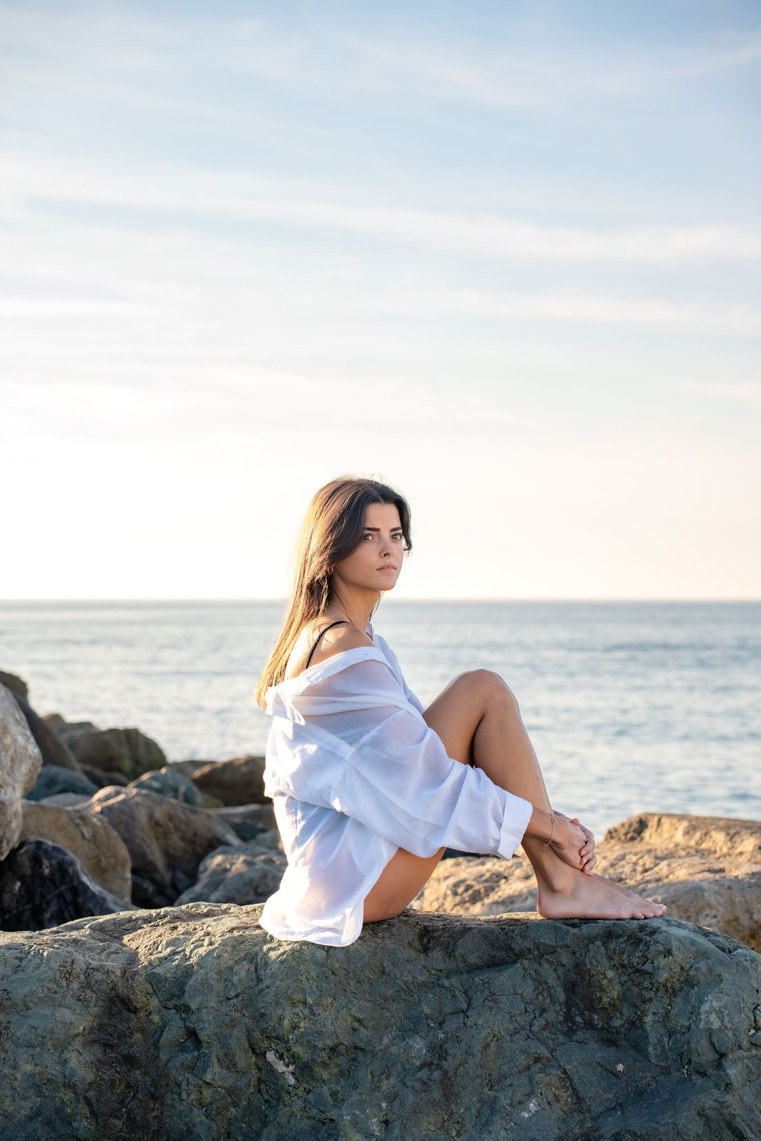Portrait of a woman on the beach in warm natural light, with ocean and soft tones creating a cinematic mood.
