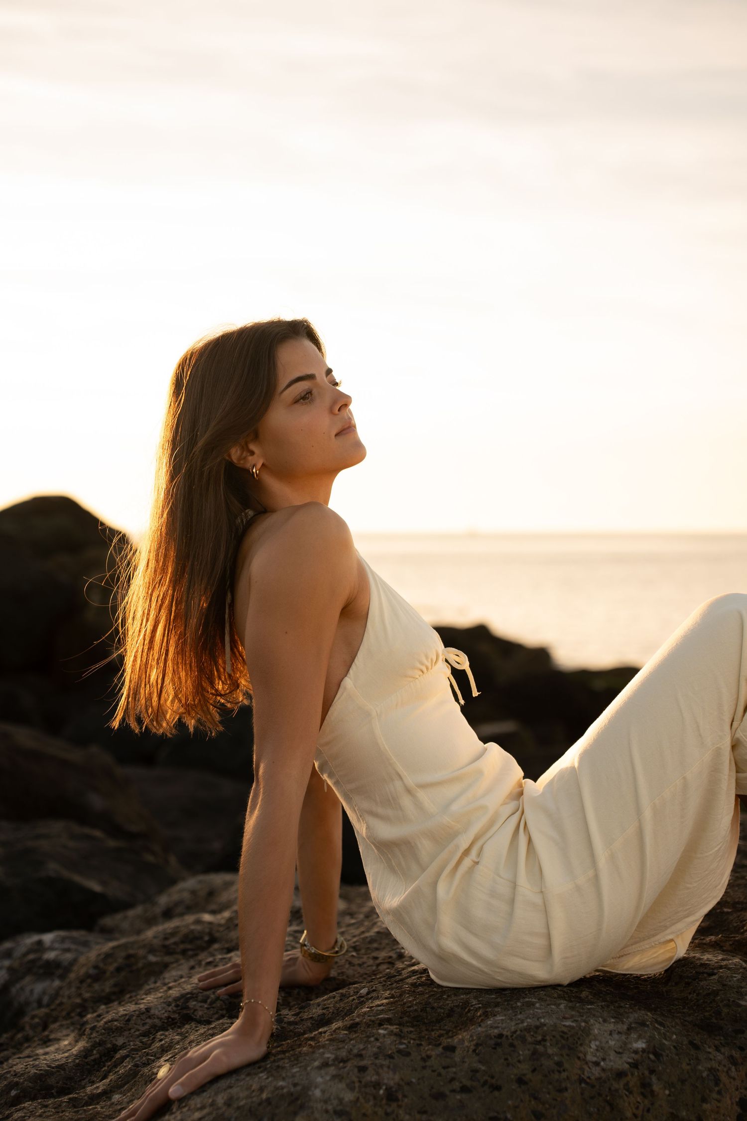 Portrait of a woman on the beach in warm natural light, with ocean and soft tones creating a cinematic mood.