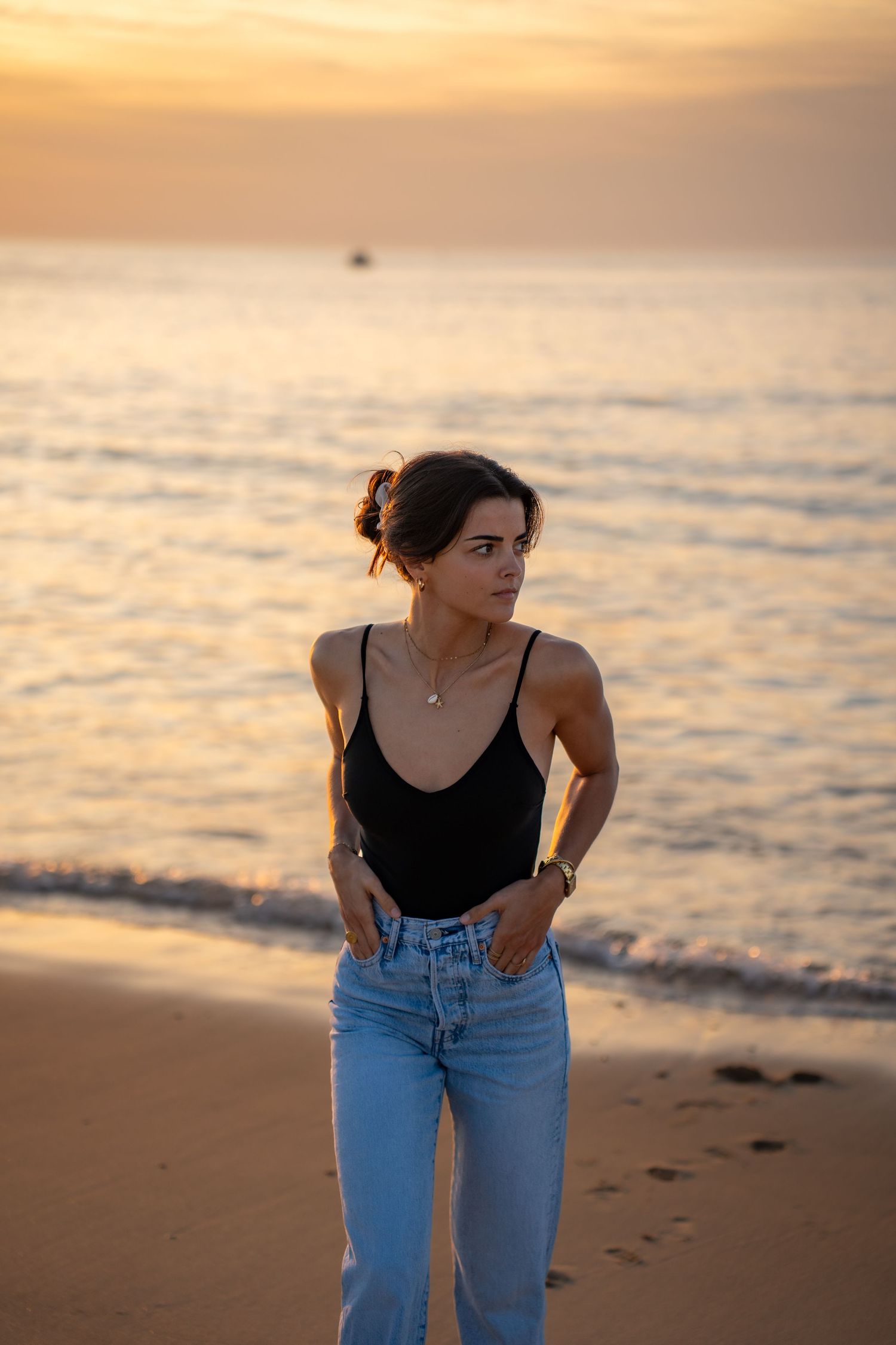 Portrait of a woman on the beach in warm natural light, with ocean and soft tones creating a cinematic mood.