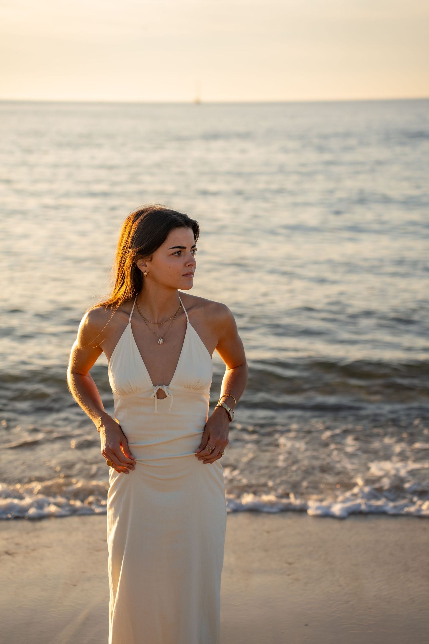 Portrait of a woman on the beach in warm natural light, with ocean and soft tones creating a cinematic mood.