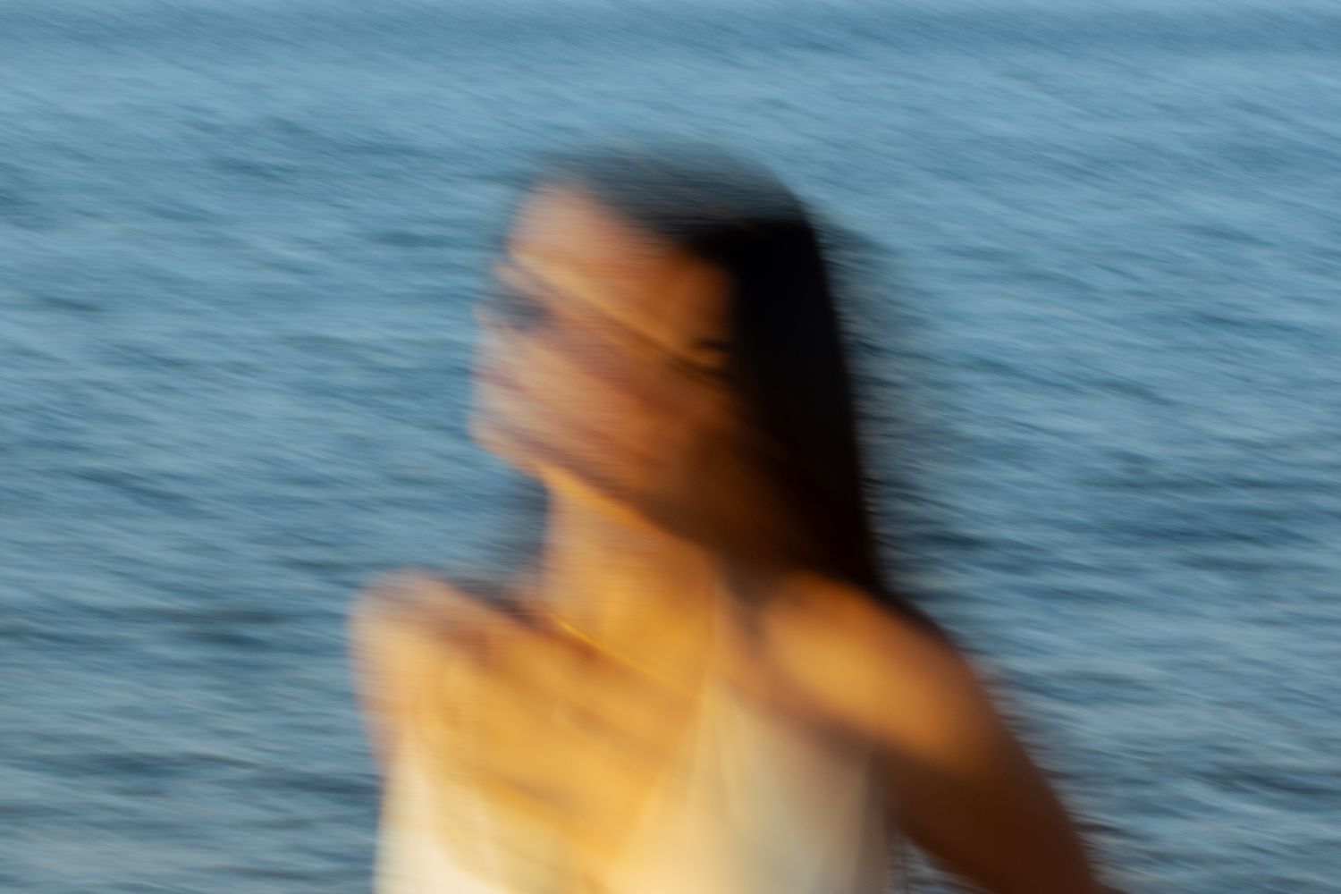 Portrait of a woman on the beach in warm natural light, with ocean and soft tones creating a cinematic mood.