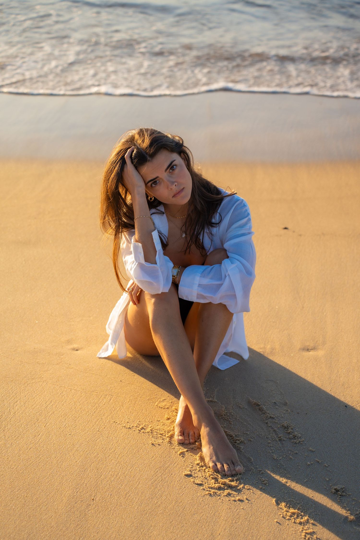 Portrait of a woman on the beach in warm natural light, with ocean and soft tones creating a cinematic mood.