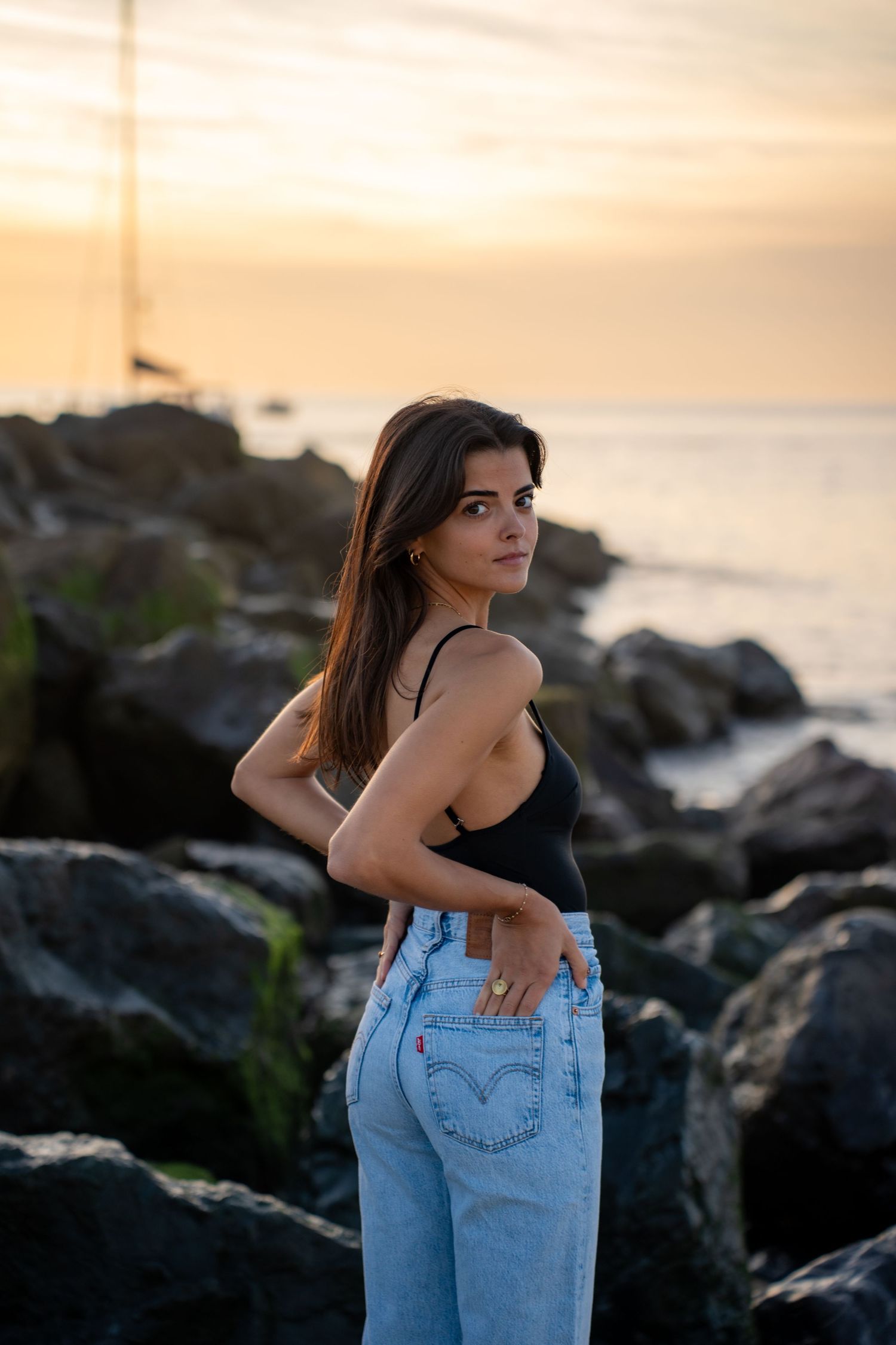 Portrait of a woman on the beach in warm natural light, with ocean and soft tones creating a cinematic mood.