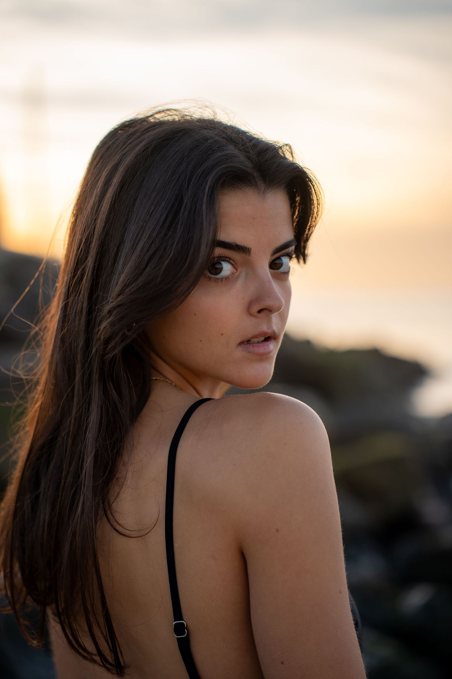 Portrait of a woman on the beach in warm natural light, with ocean and soft tones creating a cinematic mood.